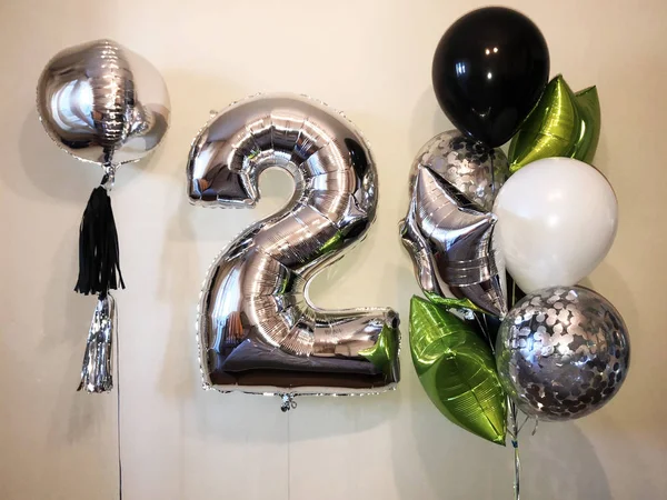 A beautiful composition of helium balloons in the form of a sphere, a large silver number 2, black, white, balloons with confetti, as well as stars of silvery color and lime