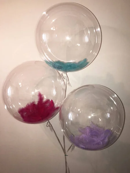 Incredibly beautiful balloon in the form of a large transparent sphere with bright feathers inside - a great option for the decor of the room for the holiday