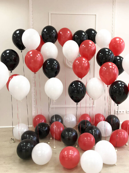 Composition of helium balloons in black, red and white. Room decorated for photo session