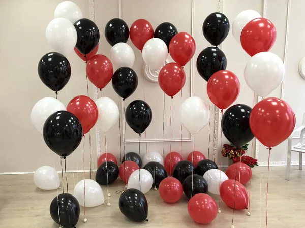 Composition of helium balloons in black, red and white. Room decorated for photo session