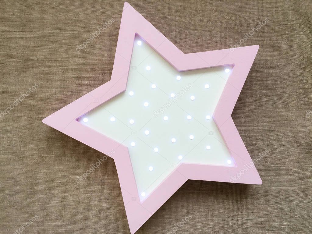 Night light in the form of a star in delicate pink and yellow tones. Decorations for decorating the bedroom of a newborn