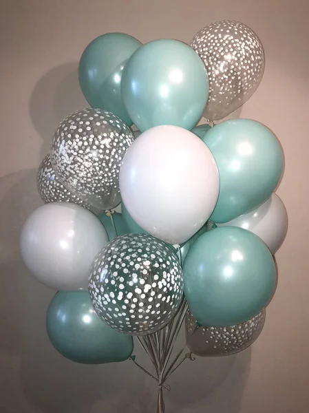 Composition of helium balloons of nacreous white color, delicate mint color and balloons with white confetti
