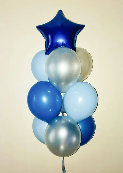 Composition from helium balloons of blue and silver color, on top of which is a bright blue star