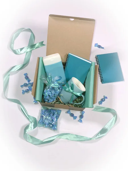 A gift set consisting of a diary, notebook, mugs, sweets and shampoo, selected with love in shades of soft turquoise, for a loved one for his holiday.