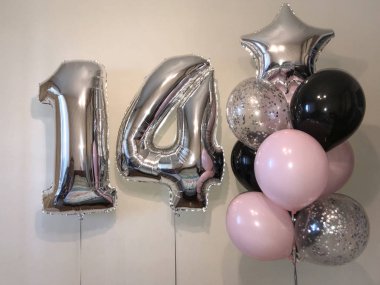 On dört - soluk pembe, gümüş, siyah, gümüş konfeti, gümüş yıldız ve büyük sayılar ile balonlar sarlak balonlar kompozisyonu. On dördüncü yıldönümü kutlamaları için oda dekorasyonu