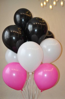 Açık bir arka plan üzerinde kırmızı, beyaz ve fuşya renklerinden oluşan helyum balonlarından kompozisyon