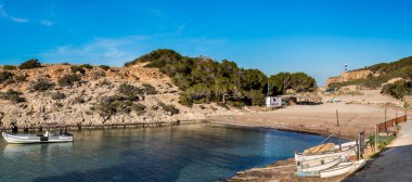 Portinatx, Ibiza, İspanya - 8 Mart 2019: Portinatx beach Ibiza Adası kuzeyinde yer alır. Sahilde bir parçası da eğlence ve Balıkçılık Tekne için bir sığınak olarak hizmet vermektedir. Arka planda biz Moscarter deniz feneri görmek