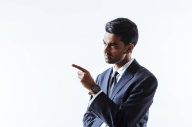 İşaret ve beyaz stüdyo arka plan üzerinde izole yan isteyen takım elbiseli yakışıklı bir adam portresi