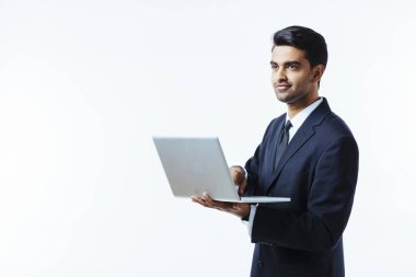 Beyaz arka plan üzerinde izole bir dizüstü bilgisayar üzerinde çalışan takım elbise bir kendine güvenen genç adam girişimci portresi