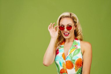 Güzel sarışın yan, yeşil studio adam izole isteyen güneş gözlüğü altından bakmak