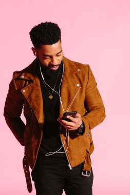 Sakallı, müzik dinlemek, telefon, pembe studio arka plan üzerinde izole bakarak serin Afrikalı-Amerikalı adam