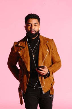 Sakallı, müzik dinlemek, kamera, pembe studio arka plan üzerinde izole bakarak serin Afrikalı-Amerikalı adam