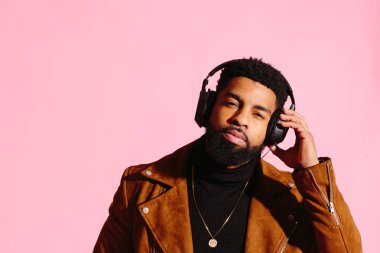Müzik dinlemek, kamera, pembe studio arka plan üzerinde izole bakarak yakışıklı ve serin Afro-Amerikan sakallı adam,
