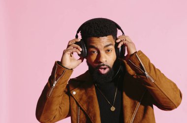 müzik dinlemek, kamera, pembe studio arka plan üzerinde izole bakarak eğlenceli, yakışıklı ve serin Afro-Amerikan sakallı adam,