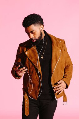 Pembe studio arka plan üzerinde izole müzik, manifatura, dinlemek, yakışıklı, şık ve serin Afro-Amerikan sakallı adam,