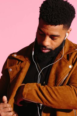 Pembe studio arka plan üzerinde izole müzik, dinlemek, yakışıklı, şık ve serin Afro-Amerikan sakallı adam,