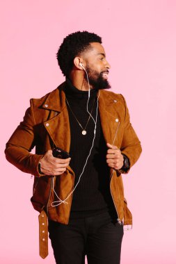 Pembe studio arka plan üzerinde izole müzik, dinlemek, yakışıklı, şık ve serin Afro-Amerikan sakallı adam,
