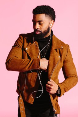Pembe studio arka plan üzerinde izole müzik, dinlemek, yakışıklı, şık ve serin Afro-Amerikan sakallı adam,
