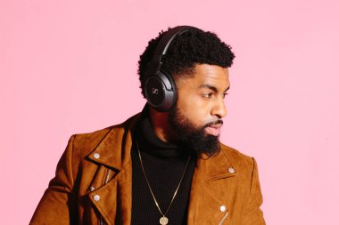 Pembe studio arka plan üzerinde izole müzik, dinlemek, yakışıklı, şık ve serin Afro-Amerikan sakallı adam,