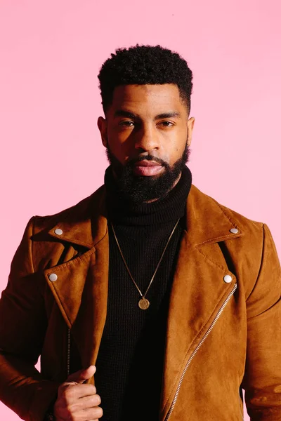 Kamera, pembe studio arka plan üzerinde izole bakarak eğlenceli, yakışıklı ve serin Afro-Amerikan sakallı adam,