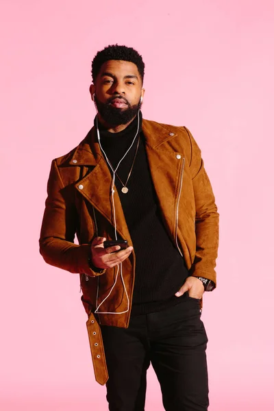 Pembe studio arka plan üzerinde izole müzik, dinlemek, yakışıklı, şık ve serin Afro-Amerikan sakallı adam,