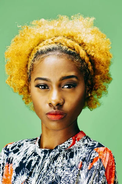 Dikey yeşil bir arka plan önünde ağartılmış kıvırcık saçlı güzel bir genç kız portresi