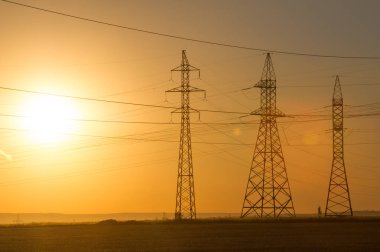 Yüksek gerilim enerji nakil hattı. Enerji ayağı. Gün batımı, şafakta. Elektrik