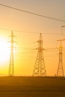 Yüksek gerilim enerji nakil hattı. Enerji ayağı. Gün batımı, şafakta. Elektrik