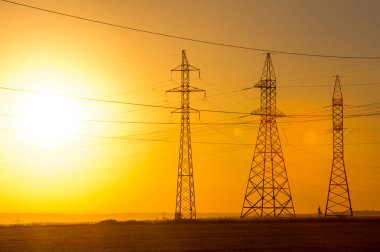 Yüksek gerilim enerji nakil hattı. Enerji ayağı. Gün batımı, şafakta. Elektrik