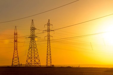 Yüksek gerilim enerji nakil hattı. Enerji ayağı. Gün batımı, şafakta. Elektrik