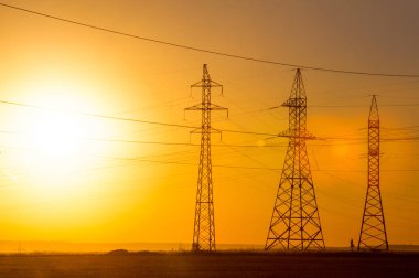 Yüksek gerilim enerji nakil hattı. Enerji ayağı. Gün batımı, şafakta. Elektrik