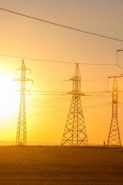 Yüksek gerilim enerji nakil hattı. Enerji ayağı. Gün batımı, şafakta. Elektrik