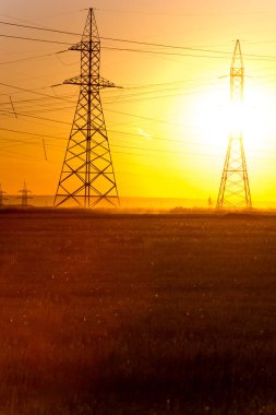 Yüksek gerilim enerji nakil hattı. Enerji ayağı. Gün batımı, şafakta. Elektrik