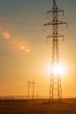 Yüksek gerilim enerji nakil hattı. Enerji ayağı. Gün batımı, şafakta. Elektrik