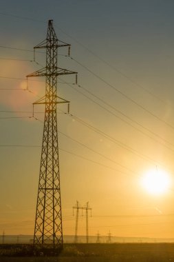 Yüksek gerilim enerji nakil hattı. Enerji ayağı. Gün batımı, şafakta. Elektrik