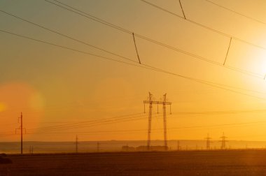 Yüksek gerilim enerji nakil hattı. Enerji ayağı. Gün batımı, şafakta. Elektrik