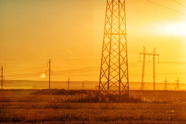 Yüksek gerilim enerji nakil hattı. Enerji ayağı. Gün batımı, şafakta. Elektrik