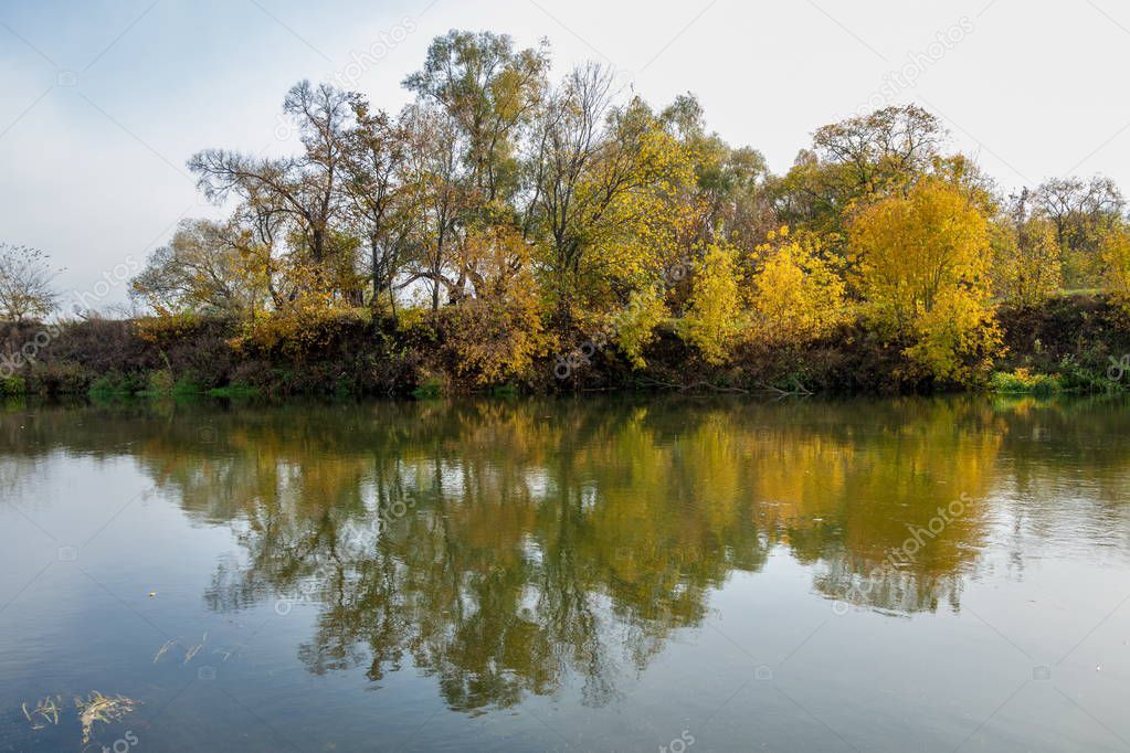 Autumn landscape. River, autumn trees of different colors. The old dry grass. Surprisingly beautiful landscape. Sad time, on the eve of winter cold
