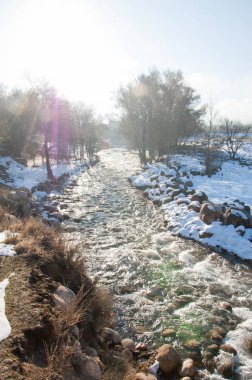 su küçük bir nehir erken ilkbahar akarsu. Bahar sahne. donmuş bir dere ile dağ manzarası