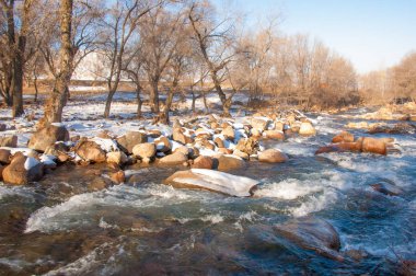 su küçük bir nehir erken ilkbahar akarsu. Bahar sahne. donmuş bir dere ile dağ manzarası
