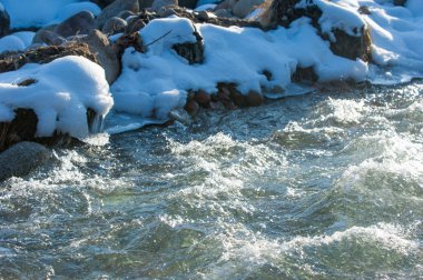 su küçük bir nehir erken ilkbahar akarsu. Bahar sahne. donmuş bir dere ile dağ manzarası