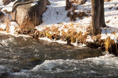 su küçük bir nehir erken ilkbahar akarsu. Bahar sahne. donmuş bir dere ile dağ manzarası