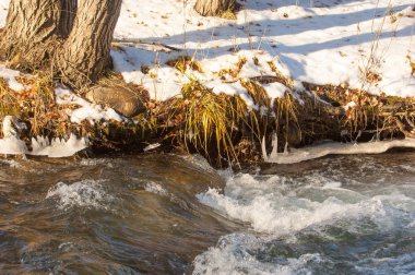 su küçük bir nehir erken ilkbahar akarsu. Bahar sahne. donmuş bir dere ile dağ manzarası