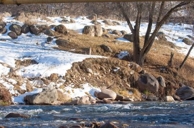 su küçük bir nehir erken ilkbahar akarsu. Bahar sahne. donmuş bir dere ile dağ manzarası
