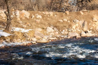su küçük bir nehir erken ilkbahar akarsu. Bahar sahne. donmuş bir dere ile dağ manzarası