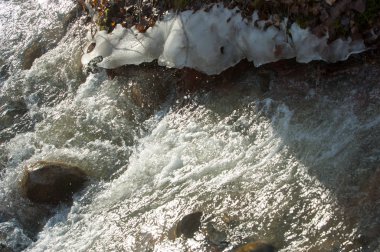 su küçük bir nehir erken ilkbahar akarsu. Bahar sahne. donmuş bir dere ile dağ manzarası