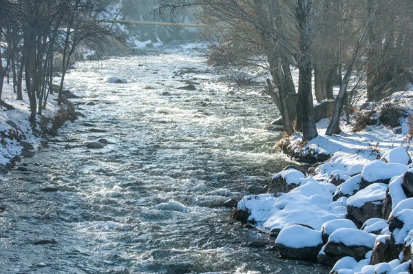 su küçük bir nehir erken ilkbahar akarsu. Bahar sahne. donmuş bir dere ile dağ manzarası