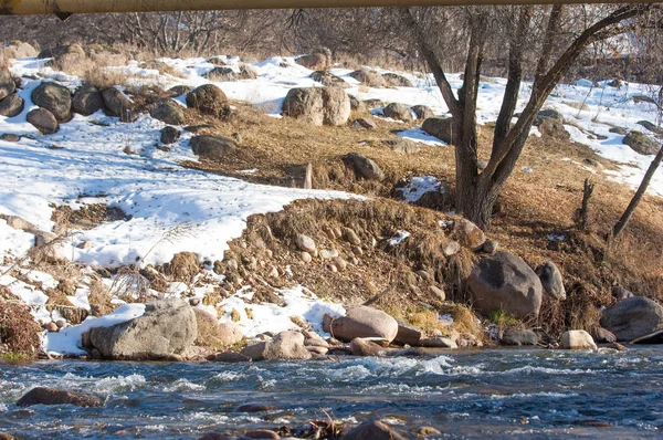 su küçük bir nehir erken ilkbahar akarsu. Bahar sahne. donmuş bir dere ile dağ manzarası