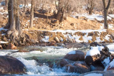 su küçük bir nehir erken ilkbahar akarsu. Bahar sahne. donmuş bir dere ile dağ manzarası
