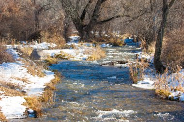 su küçük bir nehir erken ilkbahar akarsu. Bahar sahne. donmuş bir dere ile dağ manzarası